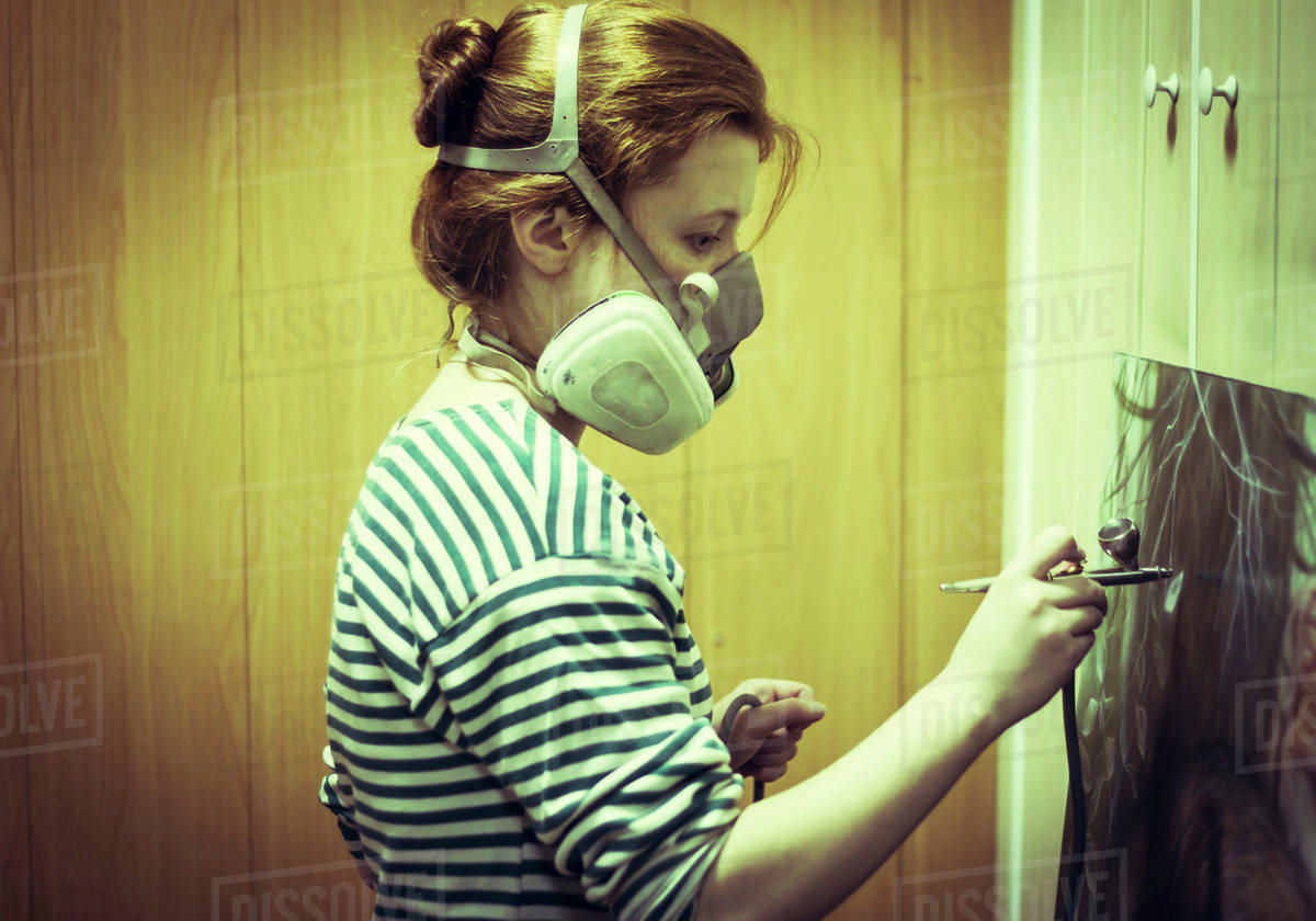 Artist in gas mask airbrushing painting in studio Stock Photo Dissolve
