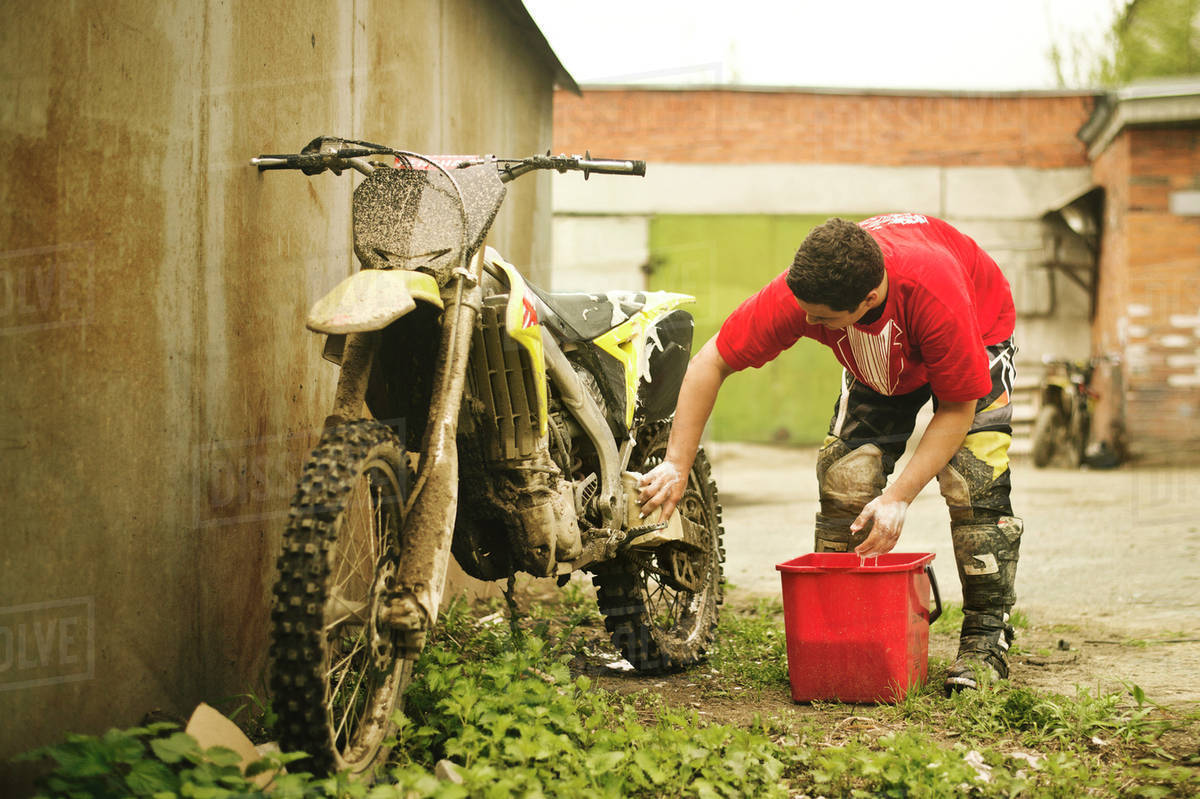 Caucasian man washing dirt bike Stock Photo Dissolve