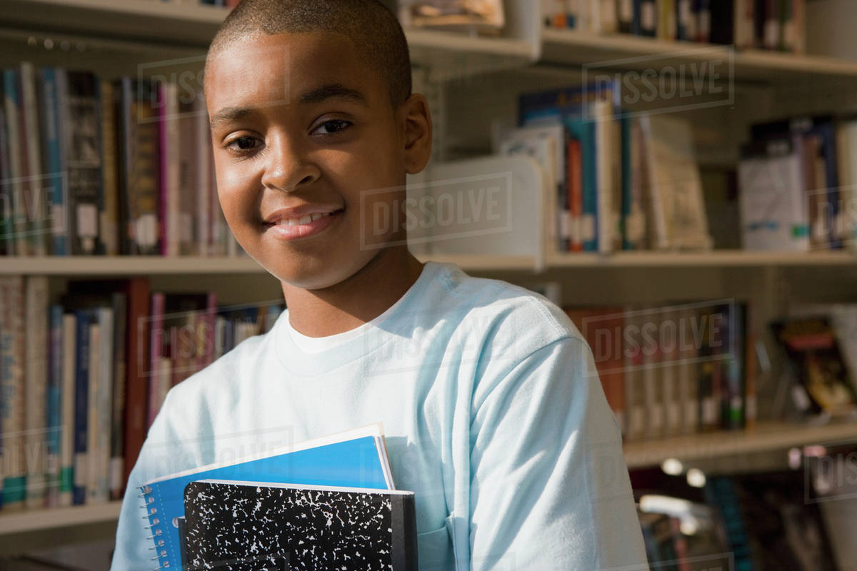 Mixed Race Boy Holding Books In Library Stock Photo Dissolve