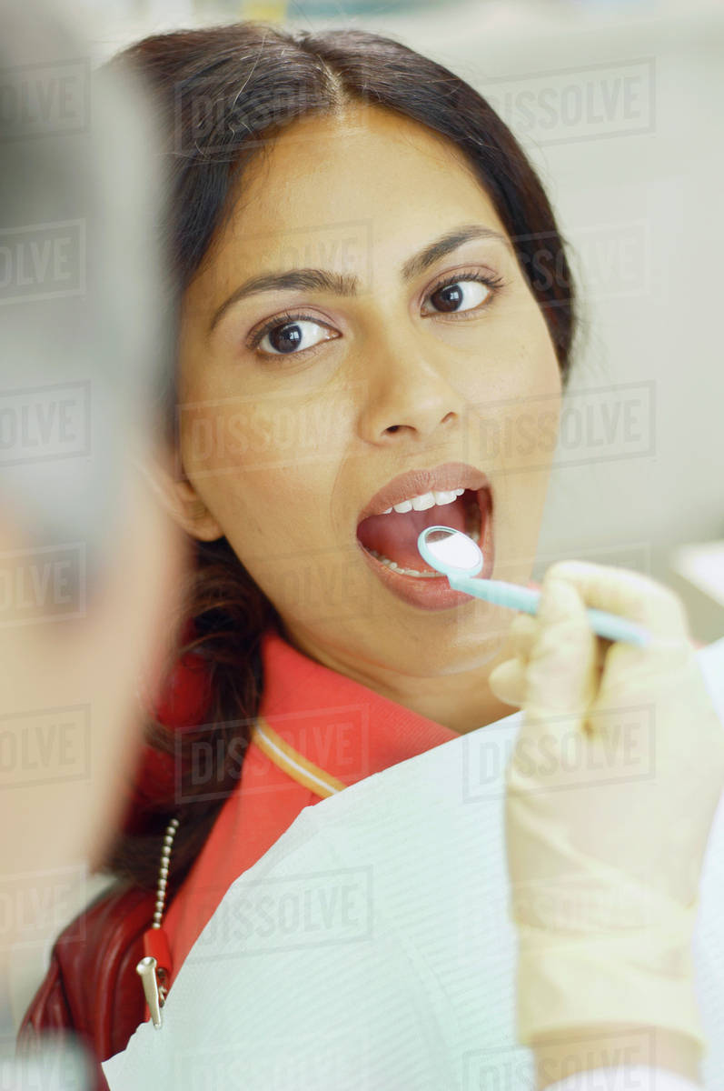 Dentist holding dental mirror in female patient's mouth Stock Photo