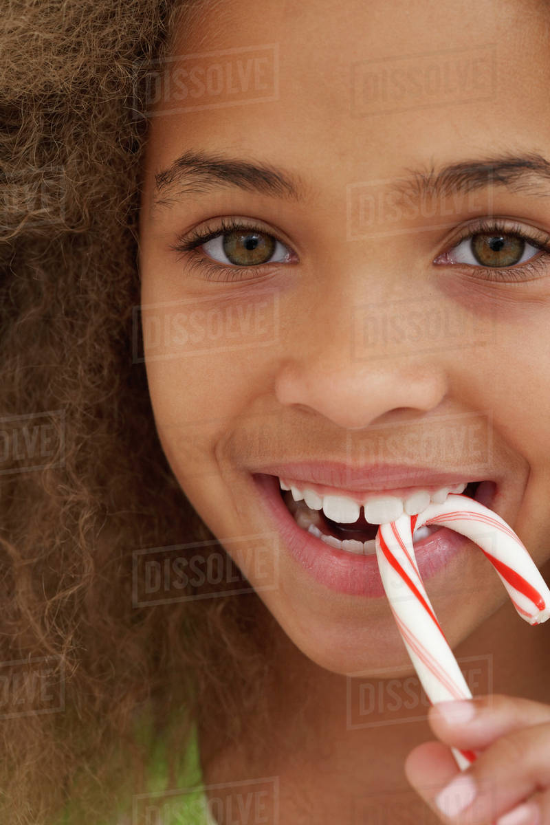 Close up of African American girl eating candy cane Stock Photo Dissolve