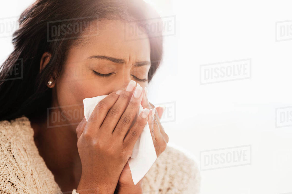 Mixed race woman blowing her nose Stock Photo Dissolve
