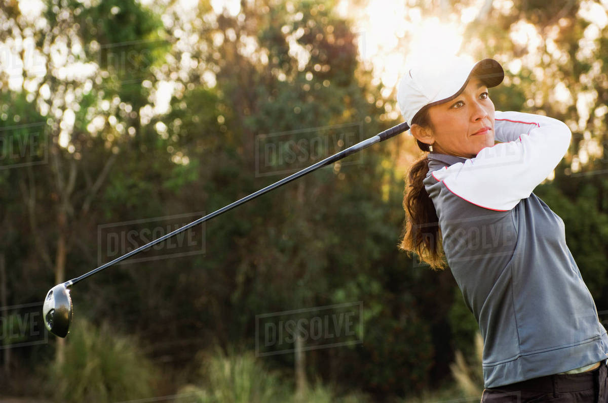 Mixed race woman playing golf on golf course Stock Photo Dissolve