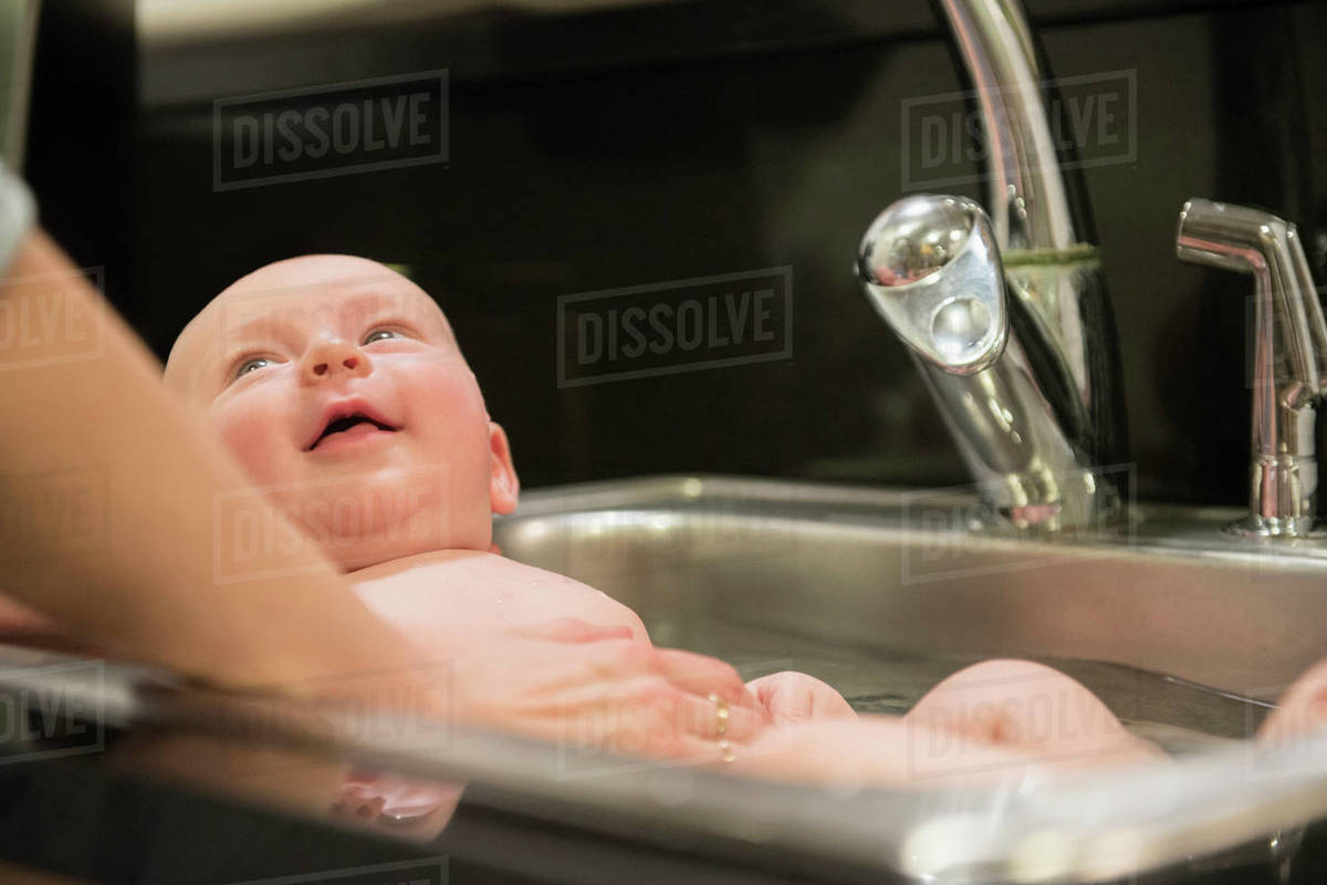 Caucasian mother bathing baby in sink Stock Photo Dissolve