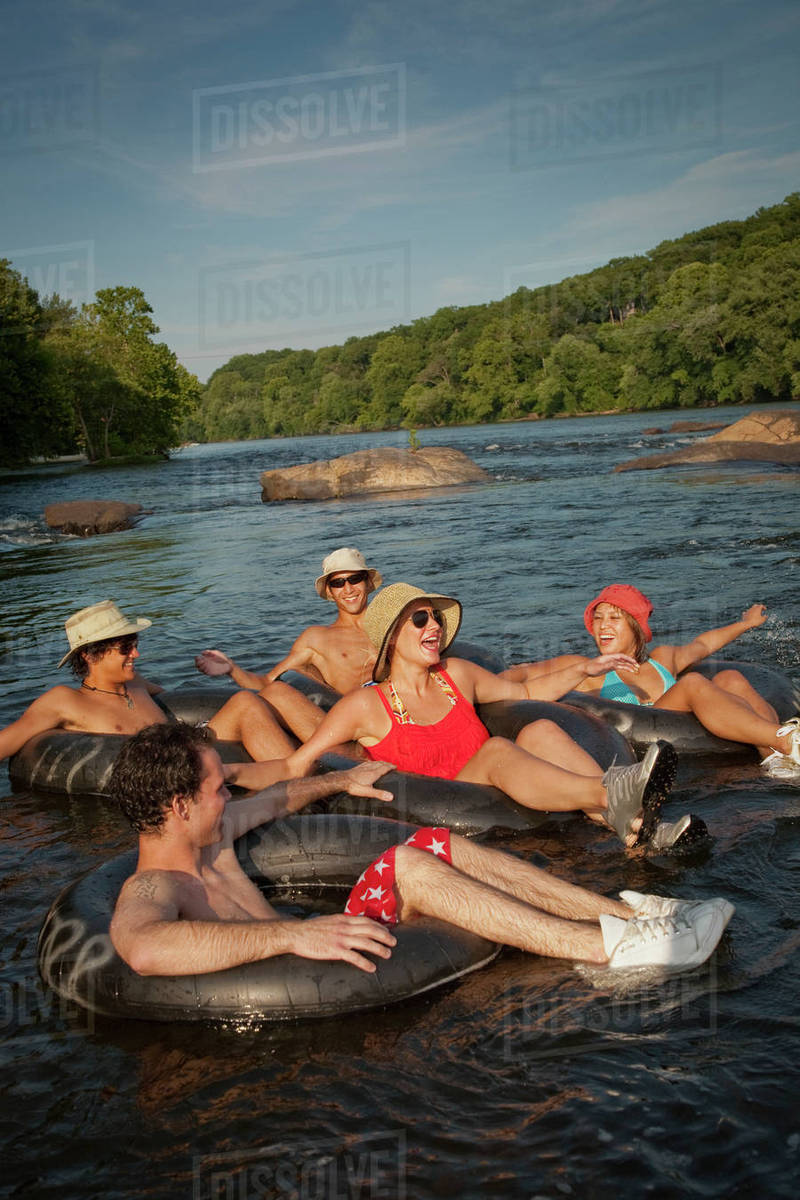 Friends floating on river in inner tubes Stock Photo Dissolve