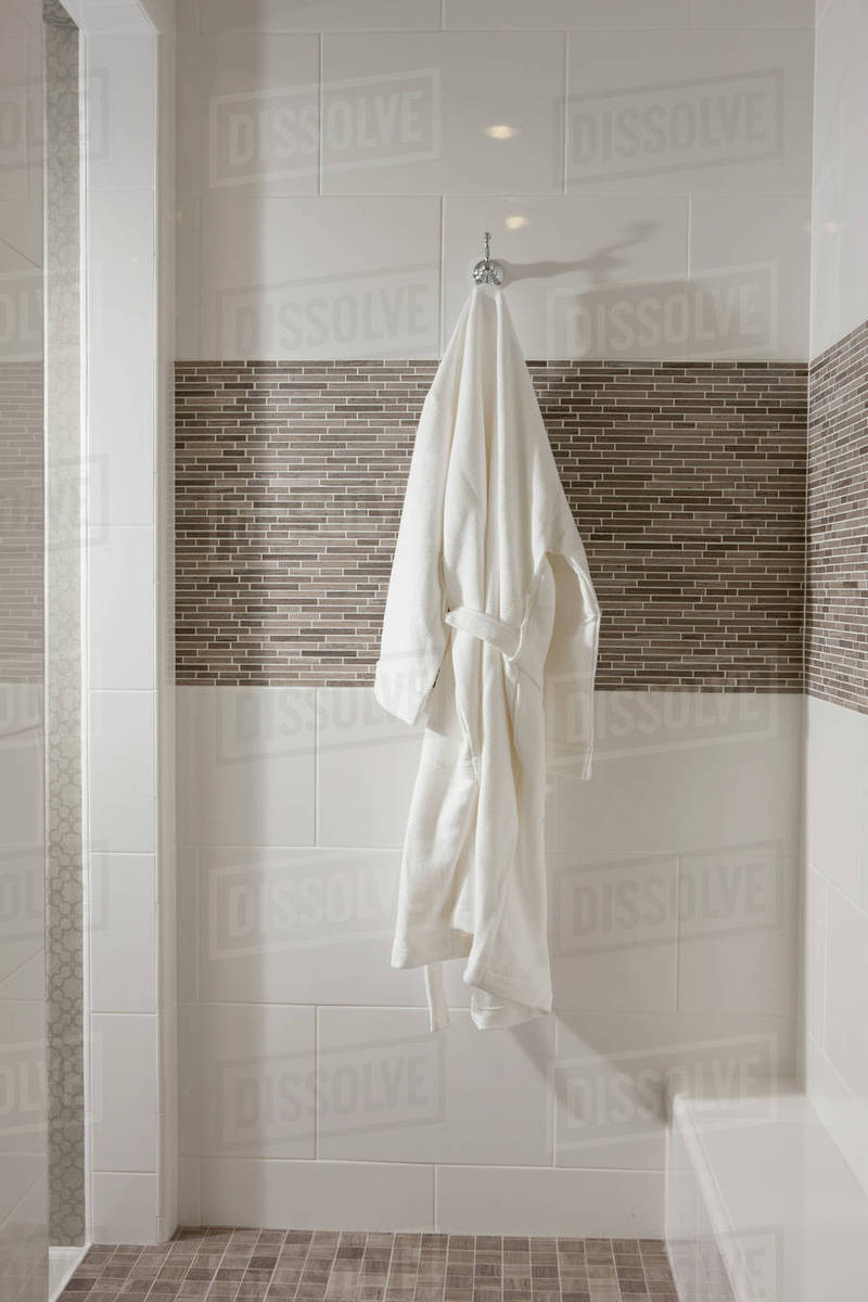 White bathrobe hanging in bathroom Stock Photo Dissolve