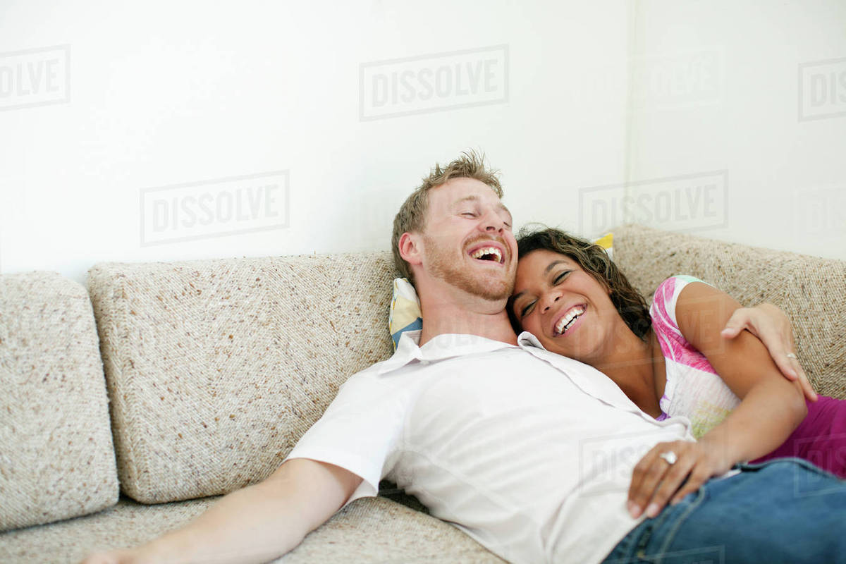 Laughing couple laying on sofa together Stock Photo Dissolve