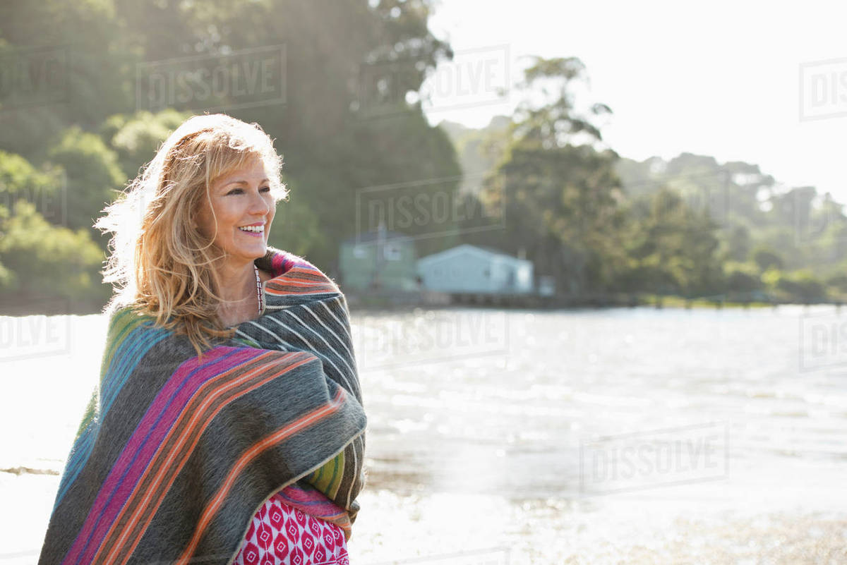 Caucasian woman wrapped in blanket on beach Stock Photo Dissolve