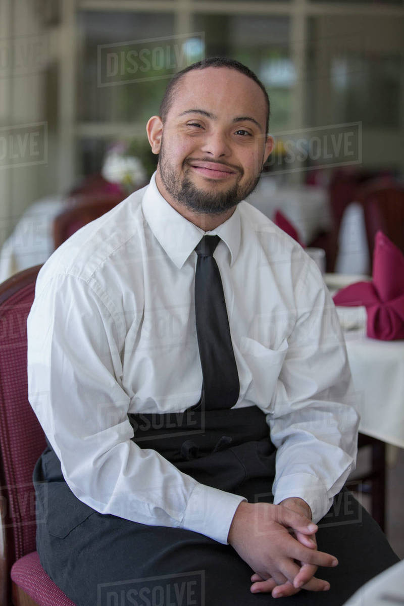 Mixed race server with down syndrome smiling in restaurant Stock