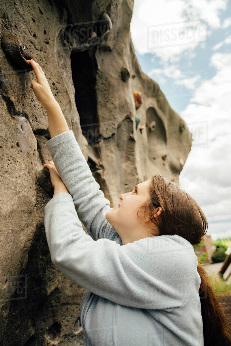 Caucasian woman climbing rock climbing wall Stock Photo Dissolve