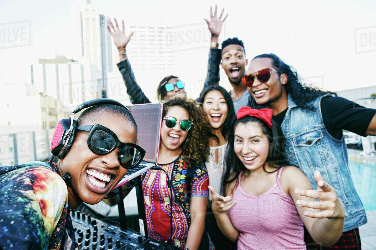 Friends smiling with DJ on urban rooftop Royalty-free stock photo