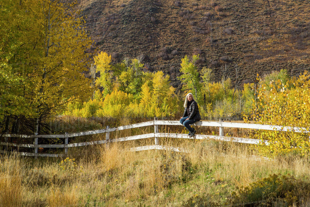 Caucasian woman sitting on wooden fence Stock Photo Dissolve