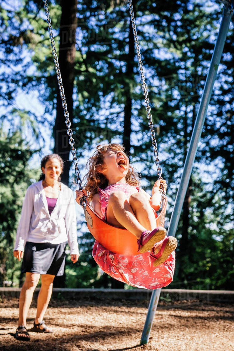 Mother Pushing Daughter On Playground Swing Stock Photo Dissolve