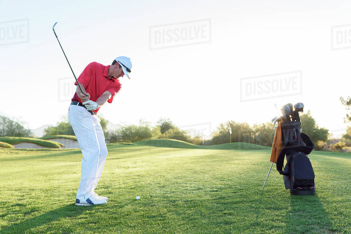 Hispanic man hitting ball on golf course Stock Photo Dissolve
