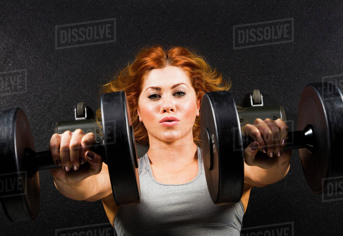 Caucasian woman doing chest presses with dumbbells in gym - Royalty ...
