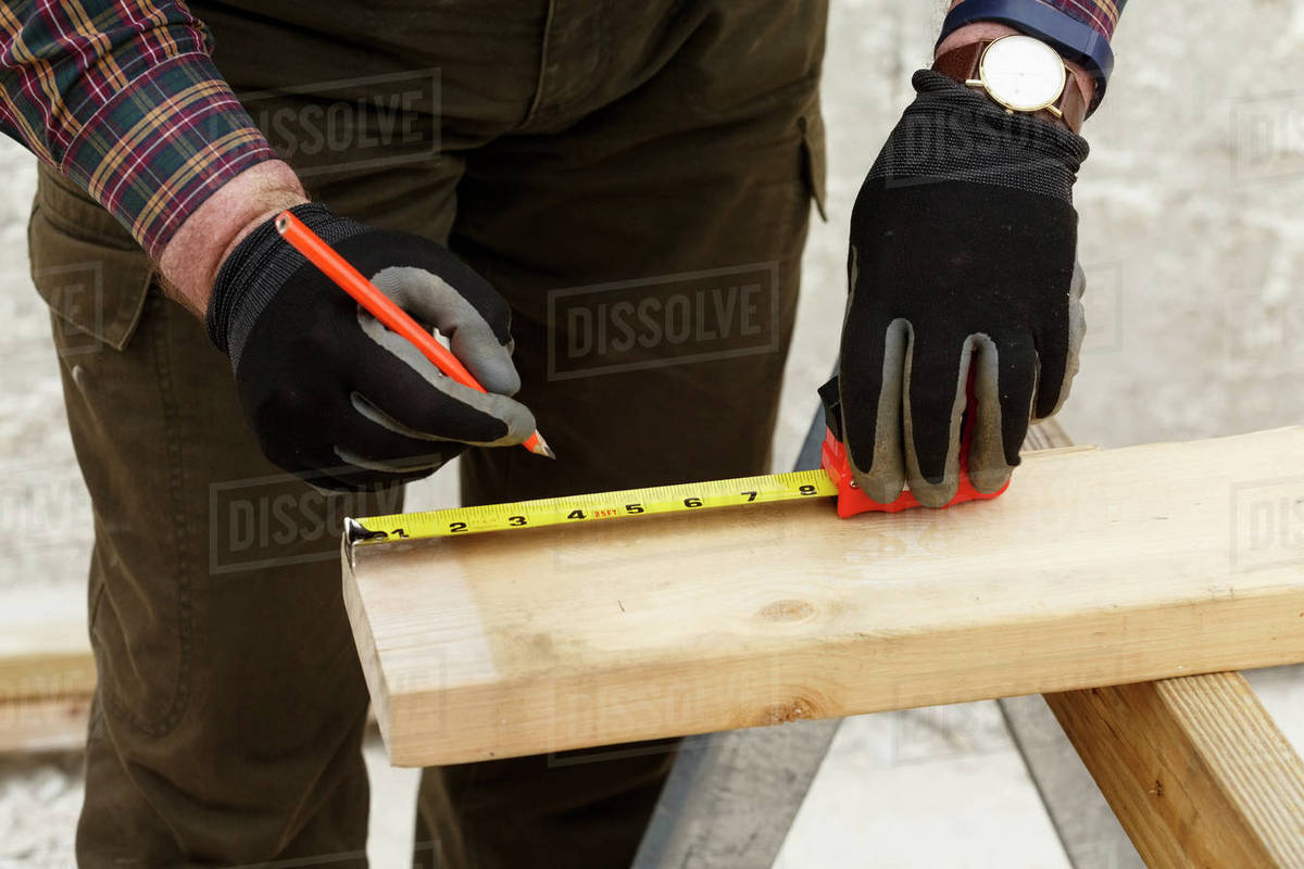 Caucasian man measuring lumber Stock Photo Dissolve