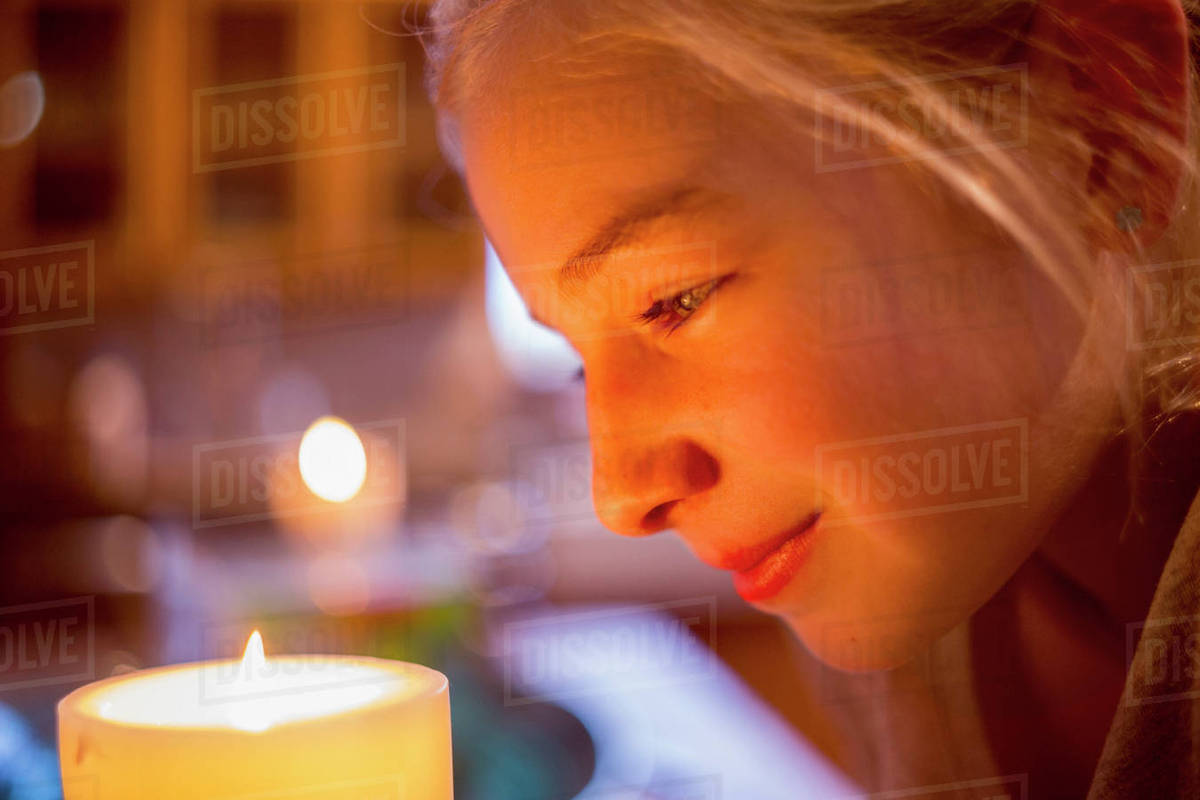 Smiling Caucasian girl watching candle Stock Photo Dissolve