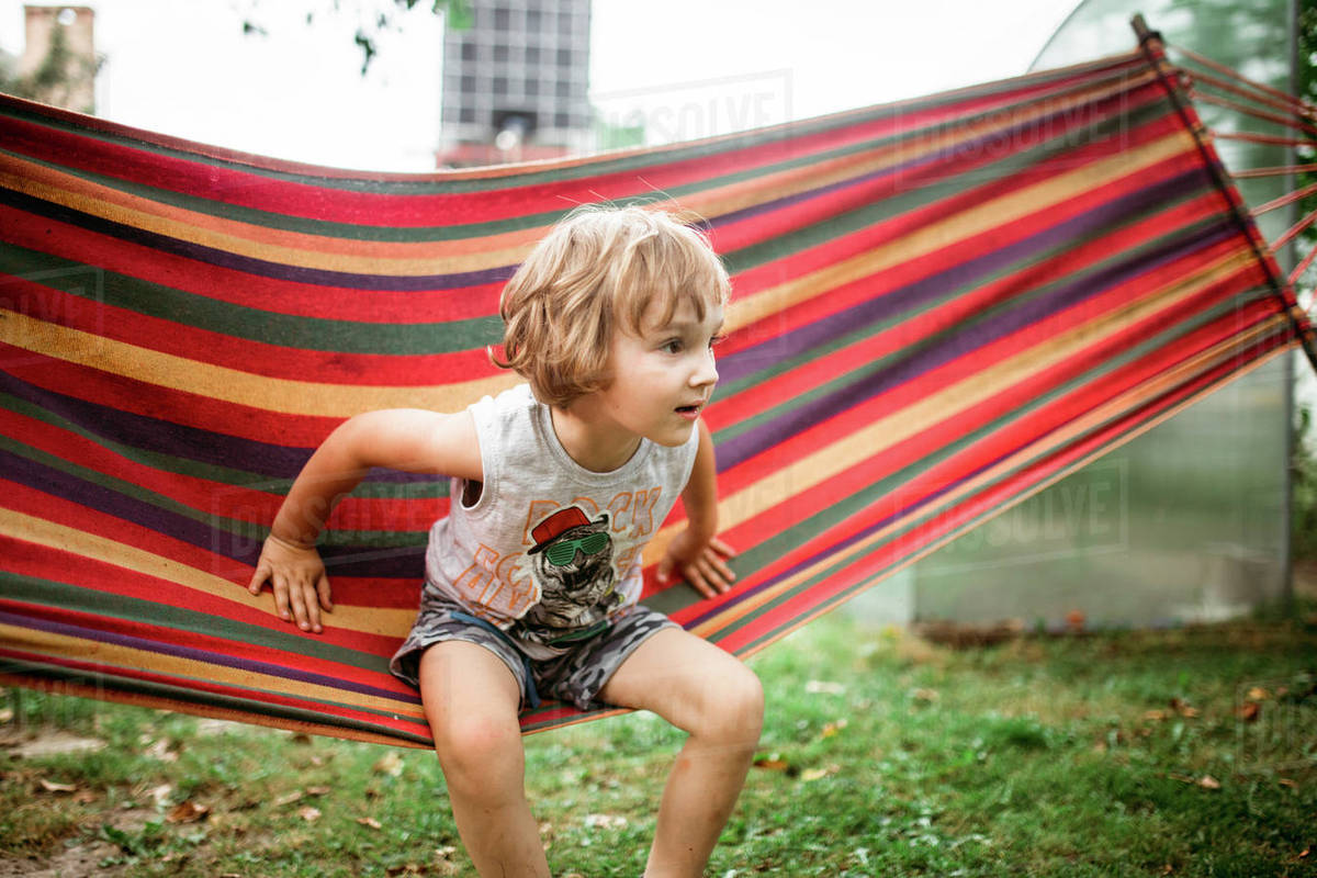 Caucasian boy sitting in hammock Stock Photo Dissolve