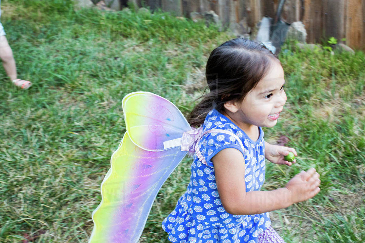 Mixed race girl running wearing fairy wings Royalty-free stock photo