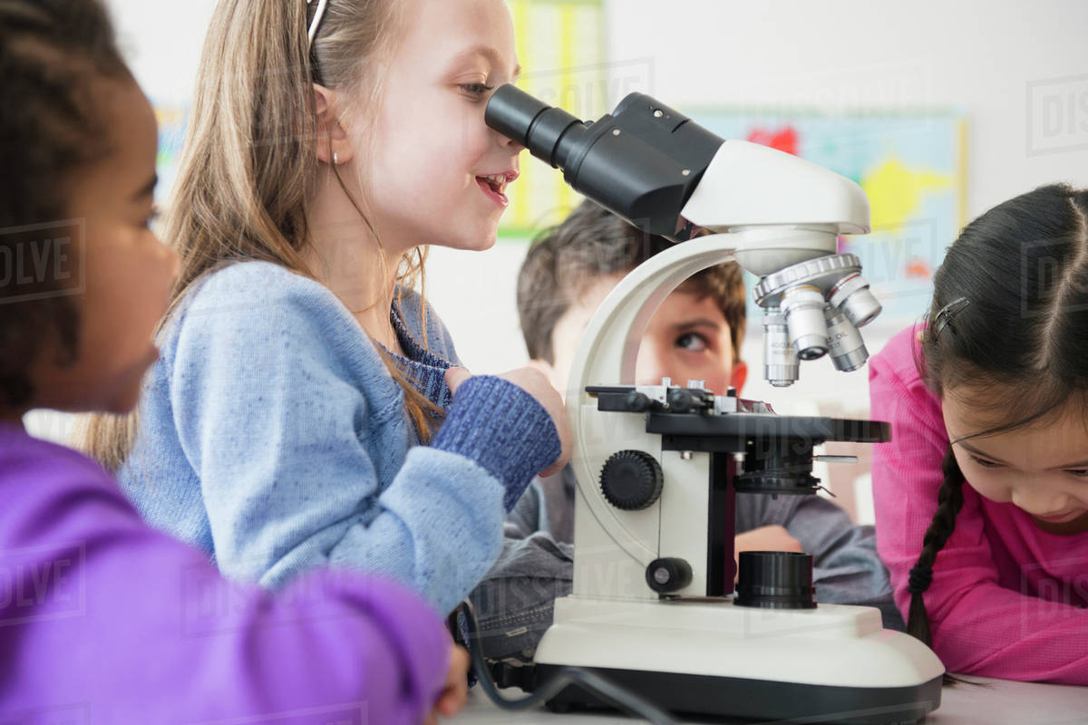 Students using microscope in classroom Stock Photo Dissolve