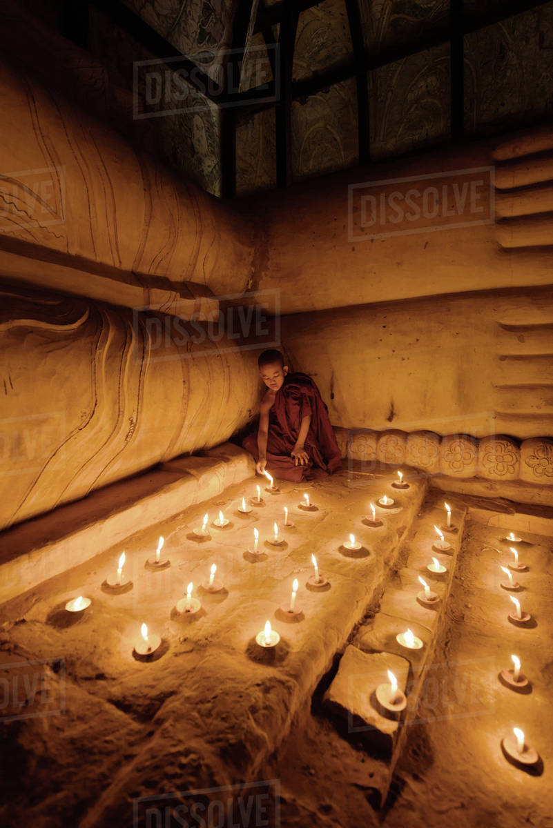 Asian monk lighting candles in temple Stock Photo Dissolve