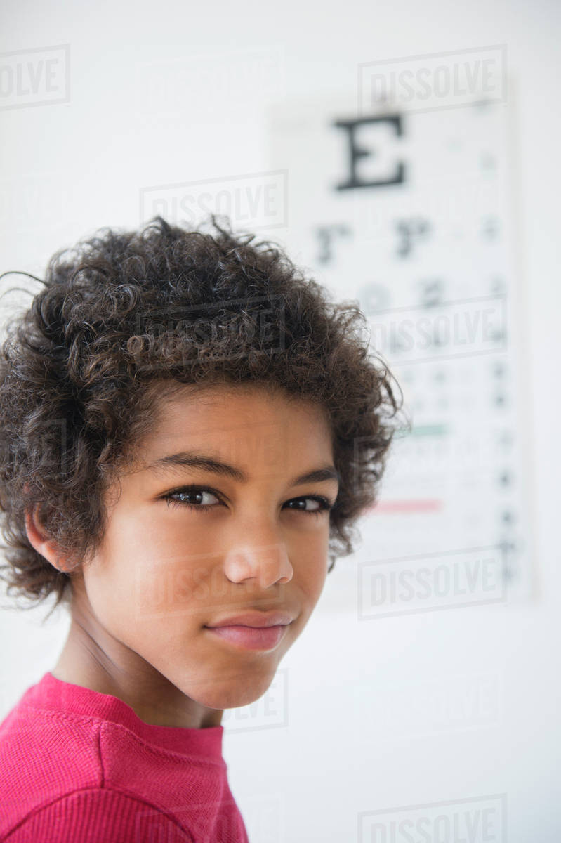 Mixed Race Boy Squinting Near Eye Chart Stock Photo Dissolve