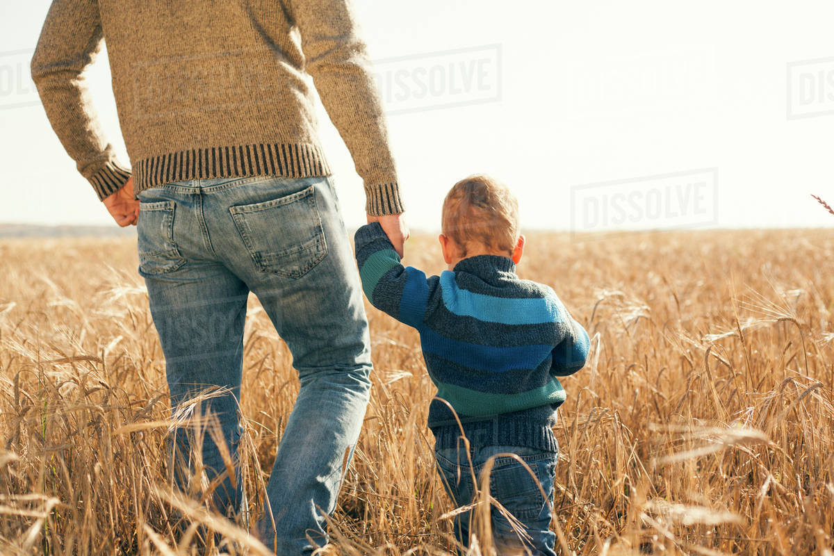 Caucasian father and son walking in rural field Stock Photo Dissolve