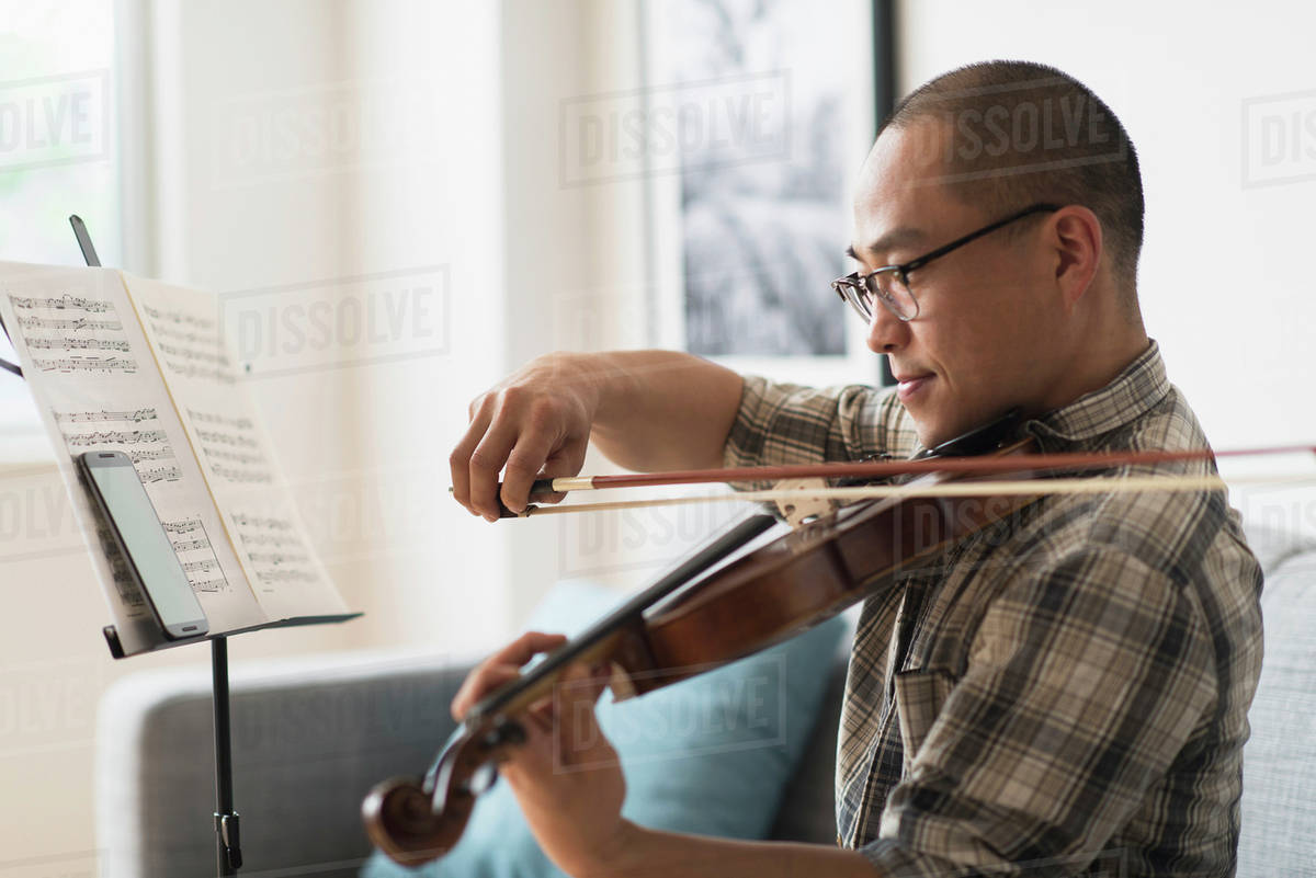 Korean musician playing violin in living room Stock Photo Dissolve