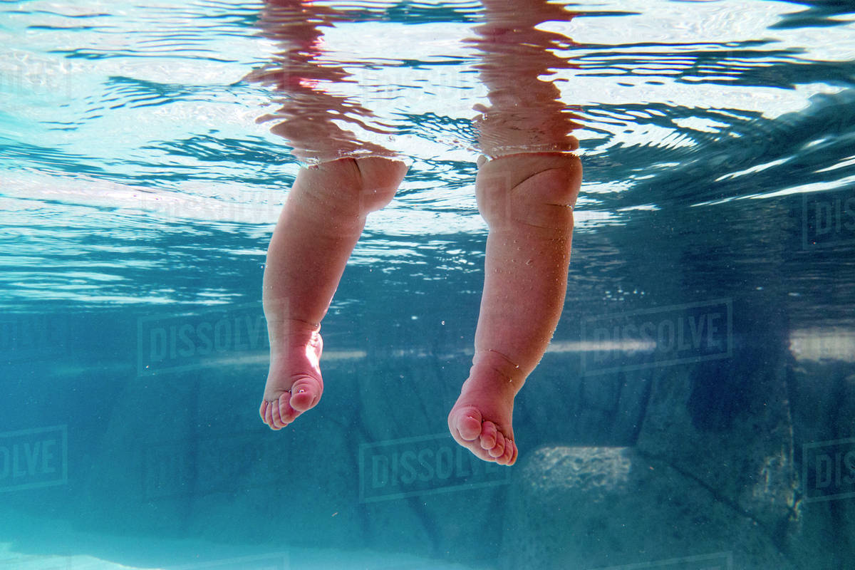 Close up of legs of baby submerged underwater Stock Photo Dissolve