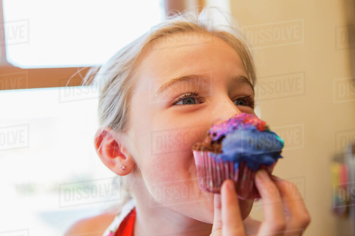 Caucasian girl eating cupcake Stock Photo Dissolve