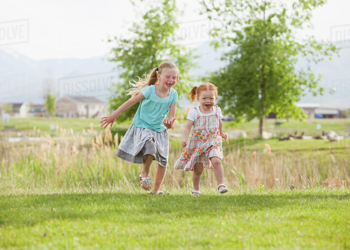 Caucasian girls running in grass Stock Photo Dissolve