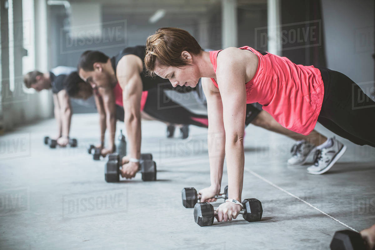 Athletes Doing Push Ups With Dumbbells On Floor Stock Photo