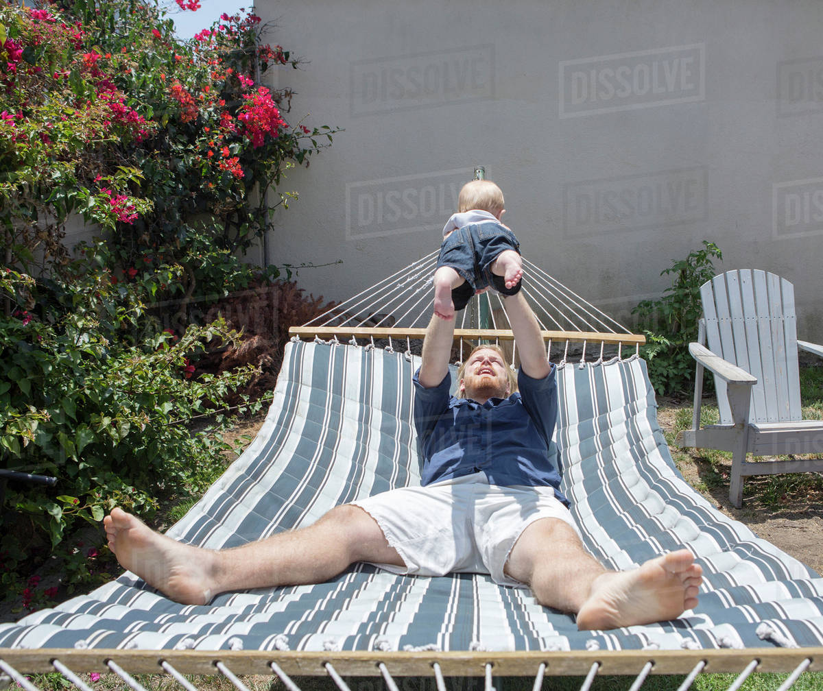 Caucasian father and son playing on hammock Stock Photo Dissolve
