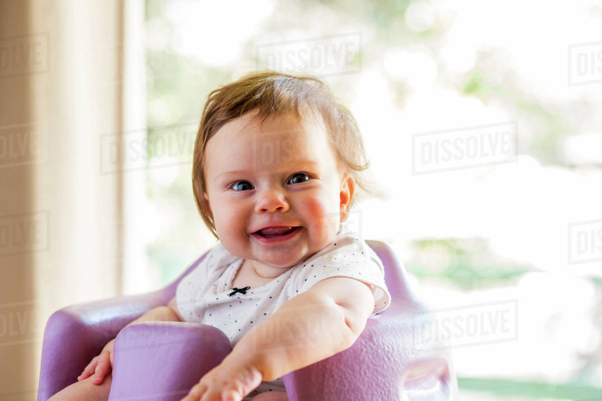 Caucasian baby girl sitting in high chair Stock Photo Dissolve