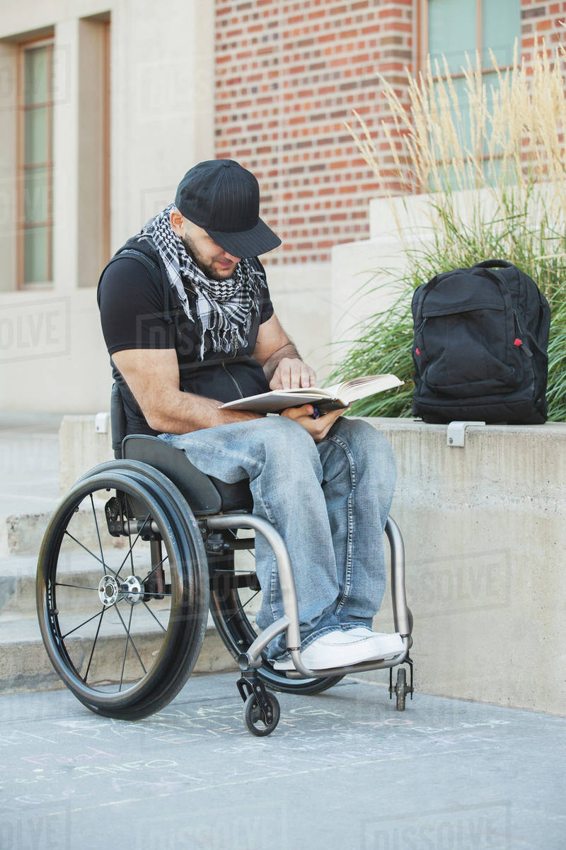 Disabled student in wheelchair reading book Stock Photo Dissolve