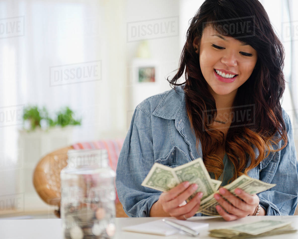 Pacific Islander woman counting money - Royalty-free Stock Photo | Dissolve