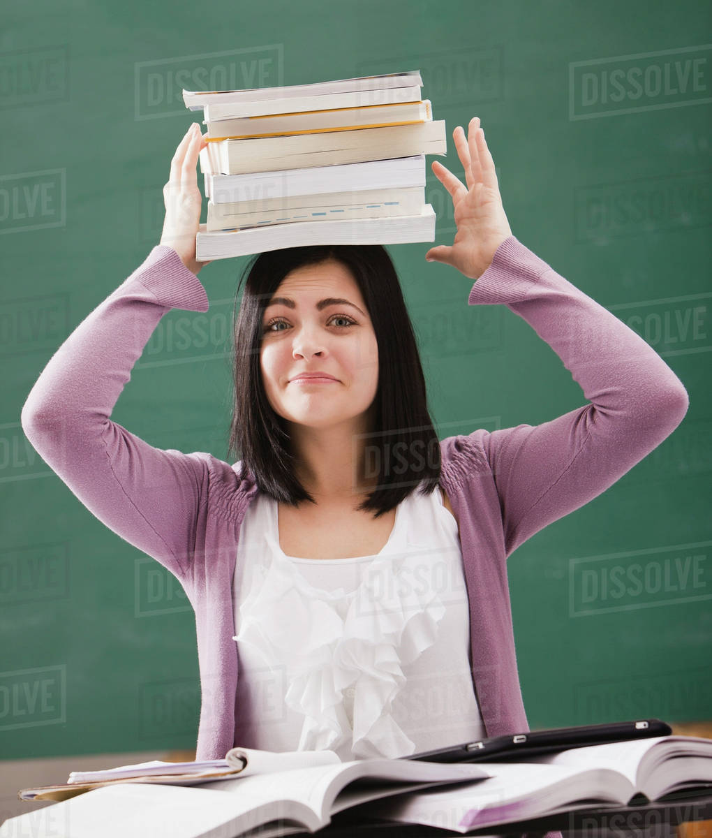 Caucasian student balancing books on head Stock Photo Dissolve