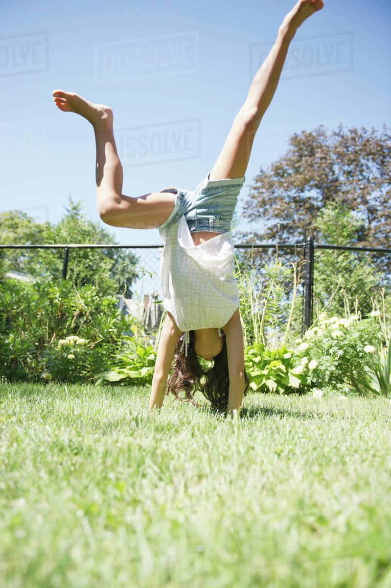Hispanic girl doing cartwheels in grass Stock Photo Dissolve