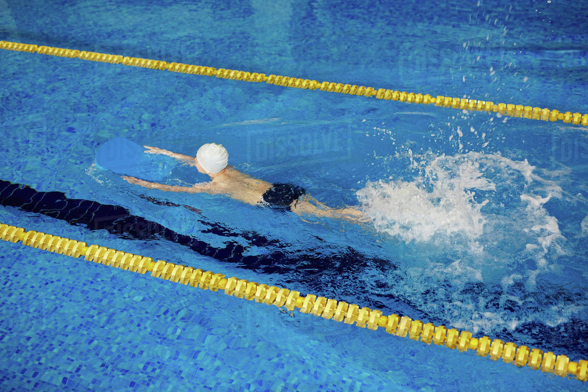 Little boy splashing water while swimming in pool Stock Photo Dissolve