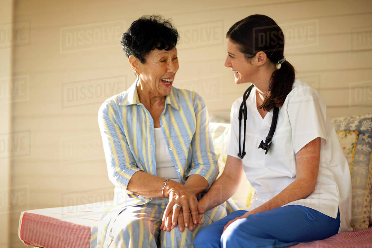 Young female nurse sitting with an elderly patient on her verandah, Royalty-free stock photo