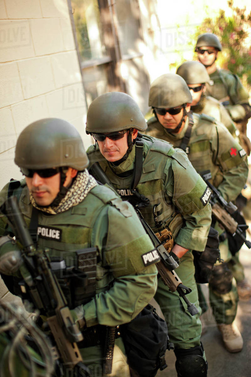 Team of armed military police holding guns while walking together - Main Image