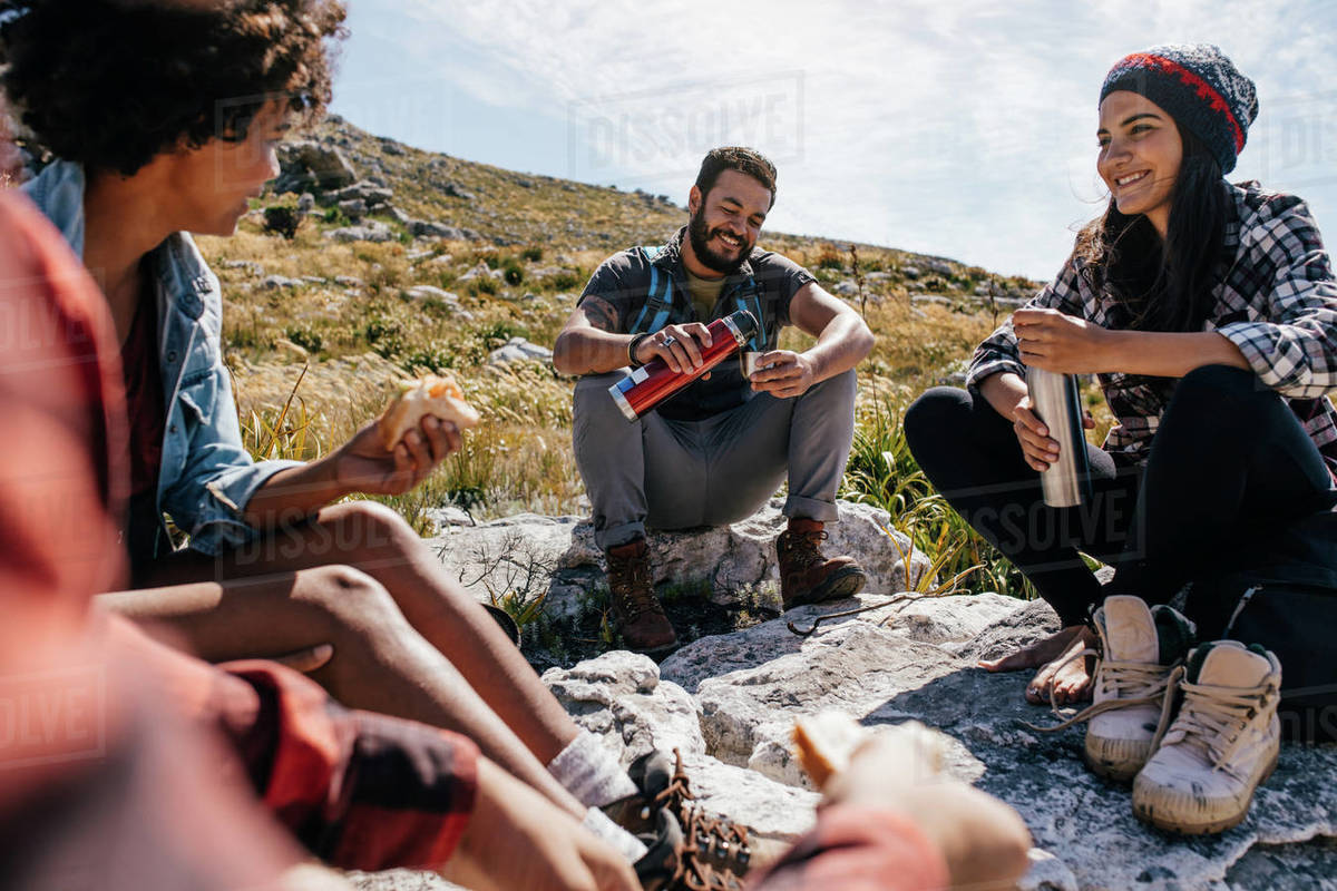 Group of hikers couple eating sandwiches and drinking coffee while