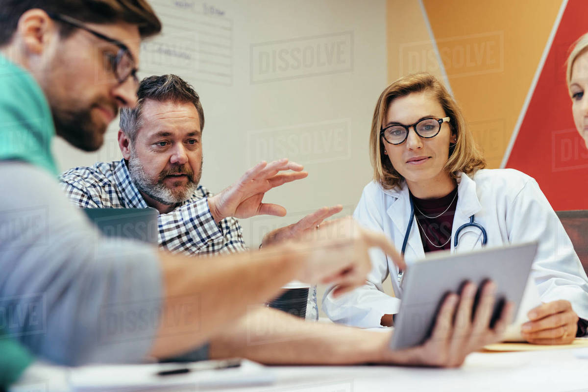 Group of healthcare workers with digital tablet meeting in hospital