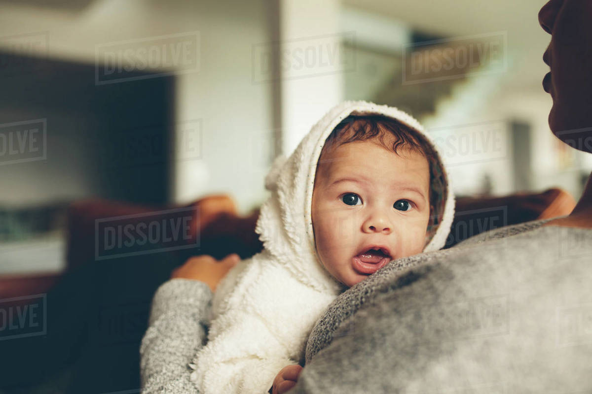 Innocent little boy resting on his mother's chest. Baby boy with mother at home. Stock Photo