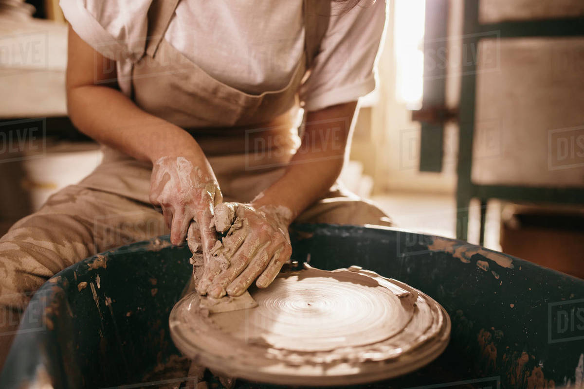 Woman flattening clay on pottery wheel in Craftswoman working