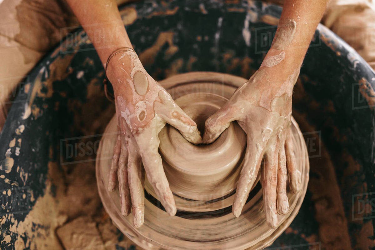 Potter making a clay pot on pottery wheel in Hands of a