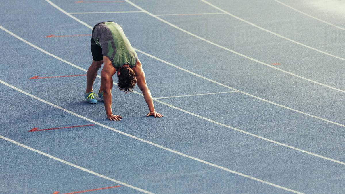 Athlete doing stretching exercises on the running track Athlete doing stretching exercises on the running track