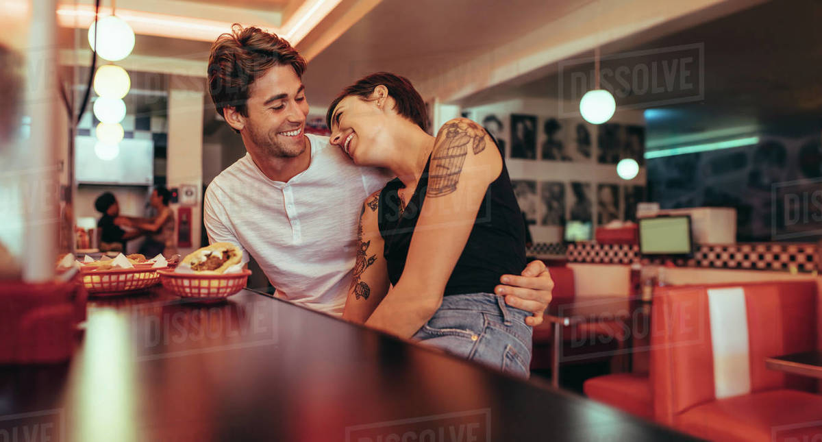 Romantic couple sitting in a restaurant with food on the table. Smiling woman sitting with her