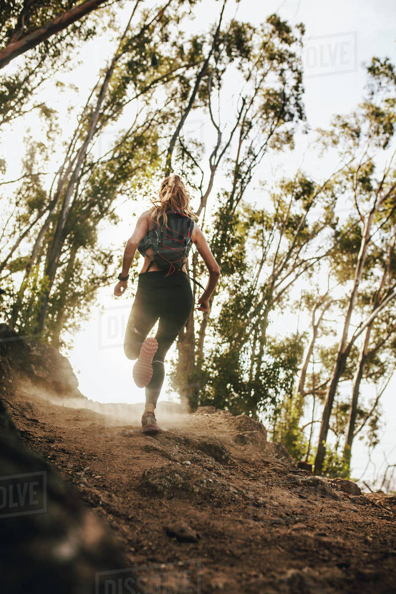 Rear view of woman running up hill. Trail running training. Fit athlete on cross country run over mountain. Royalty-free stock photo