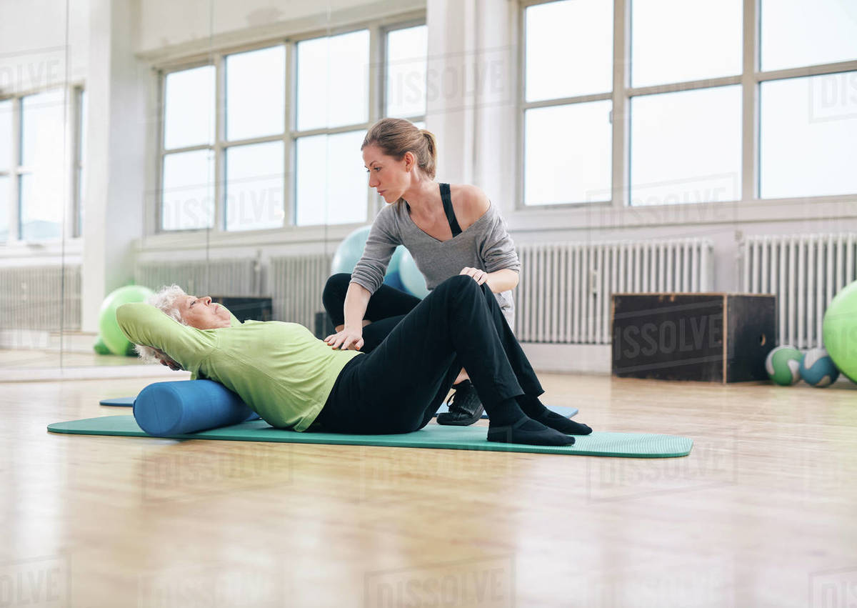 Senior woman performing back exercise on a foam roller being